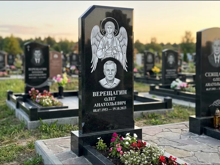Памятник с гравировкой иконы: стела с резным навершием и нимбом в золоте — гравировка образа Спасителя, высокие разросшиеся туи полукругом, работа «Мельникова» в Казани