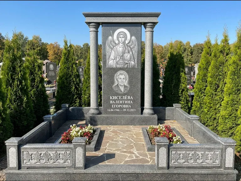 Памятник с гравировкой иконы: массивная стела с двускатным навершием-домиком — гравировка Николая Чудотворца, живая изгородь из туи, работа «Журавлёв» в Казани