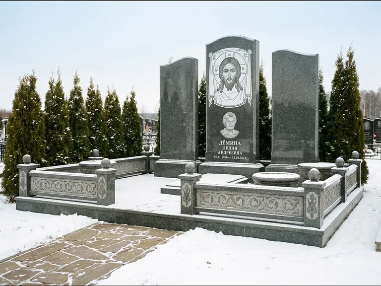 Памятник с гравировкой иконы: узкая вертикальная стела-пилон с ликом — икона в резной рамке-киоте, открытая лужайка без ограды, работа «Одинцов» в Казани