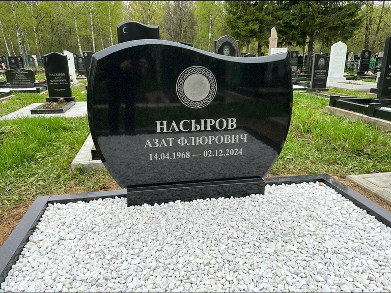 Мусульманский памятник: стела с волнообразным скошенным верхом — гравировка мечети под полумесяцем и звёздами, белая мраморная крошка с бордюром, работа «Насыров» в Казани